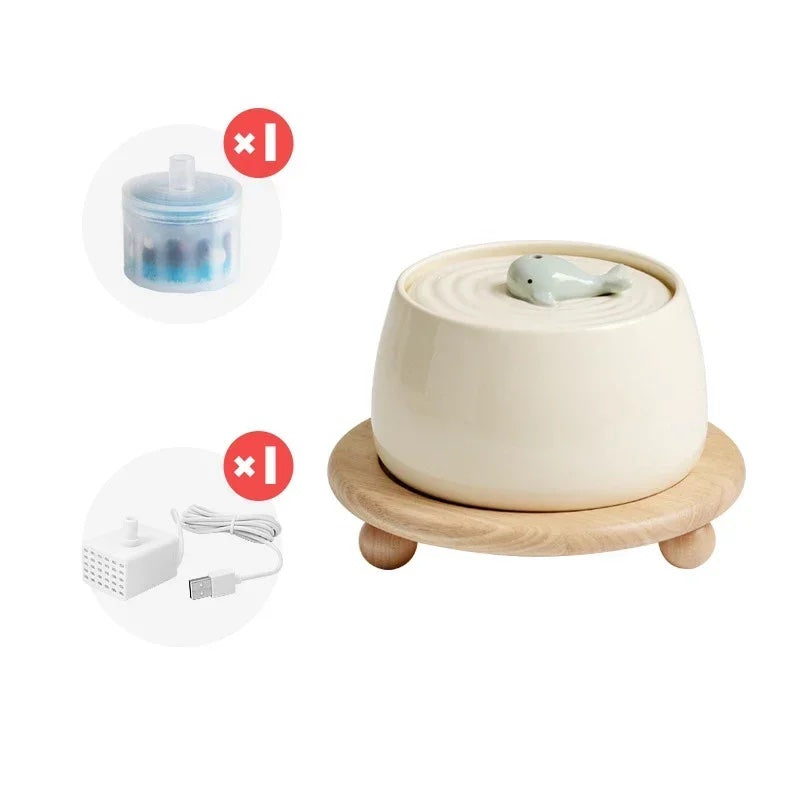 white ceramic water fountain for cats with an adorable little whale on top of it and wooden stand displayed on a white background.
