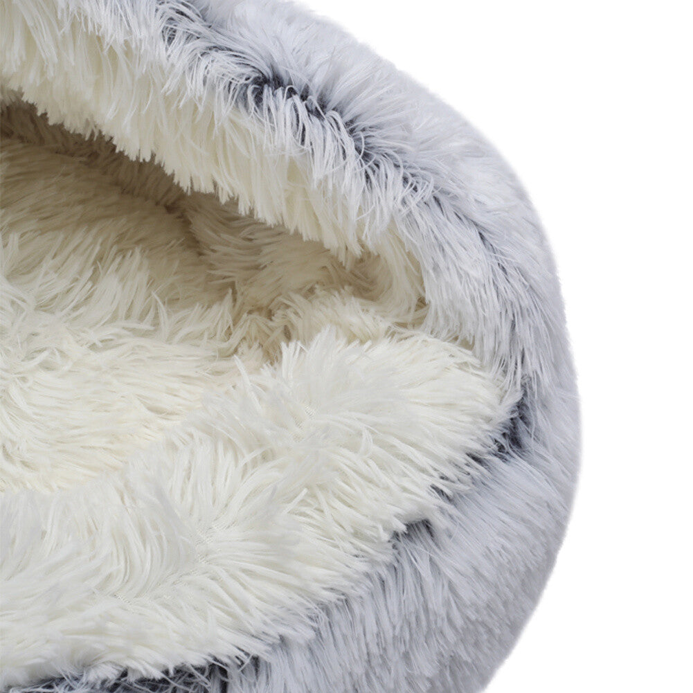 Closeup of a semi-enclosed calming cat bed with white plush interior displayed on a white background.