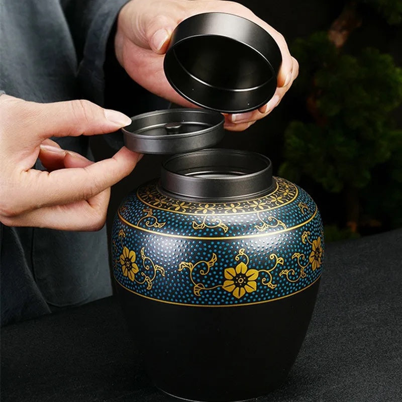 Hands opening the lid of a black pet cremation urn with blue and gold ornament, showing the inner compartments for storing ashes - elegant and secure design.