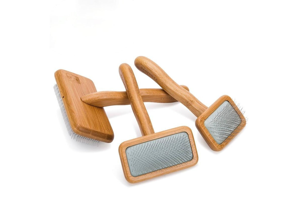 Set of wooden pet grooming brushes with metal bristles on a white background