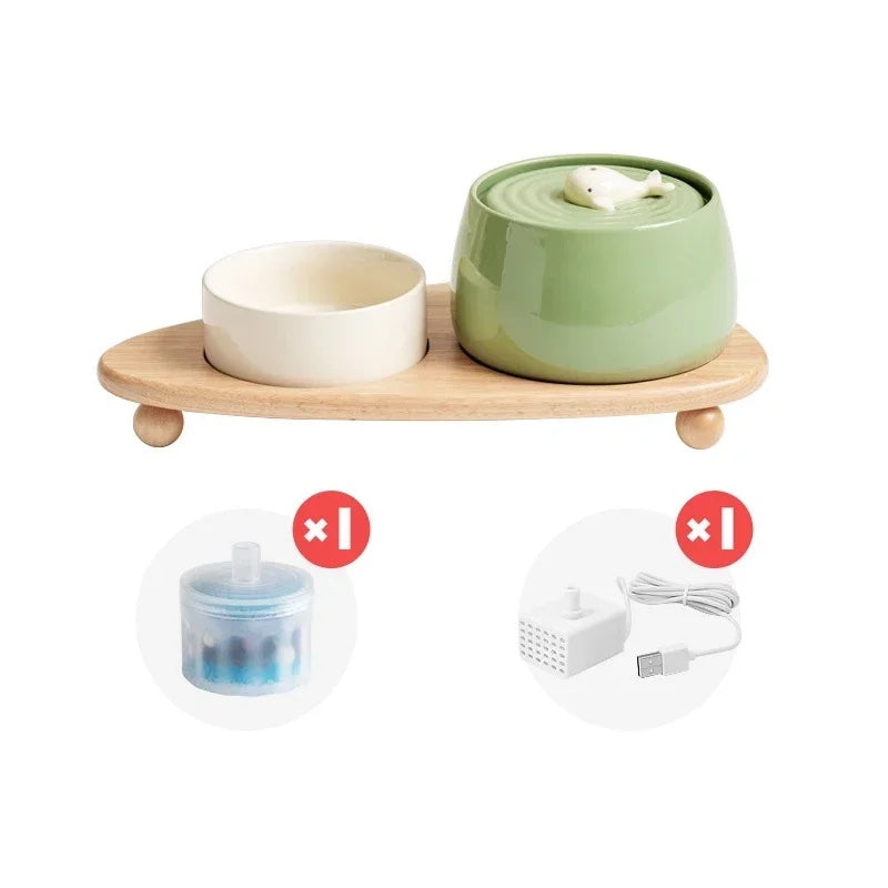 Ceramic set consist of a water fountain with a motive of a baby whale and a pet bowl with a wooden stand displayed on a white background.
