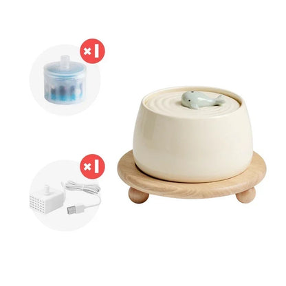 white ceramic water fountain for cats with an adorable little whale on top of it and wooden stand displayed on a white background.