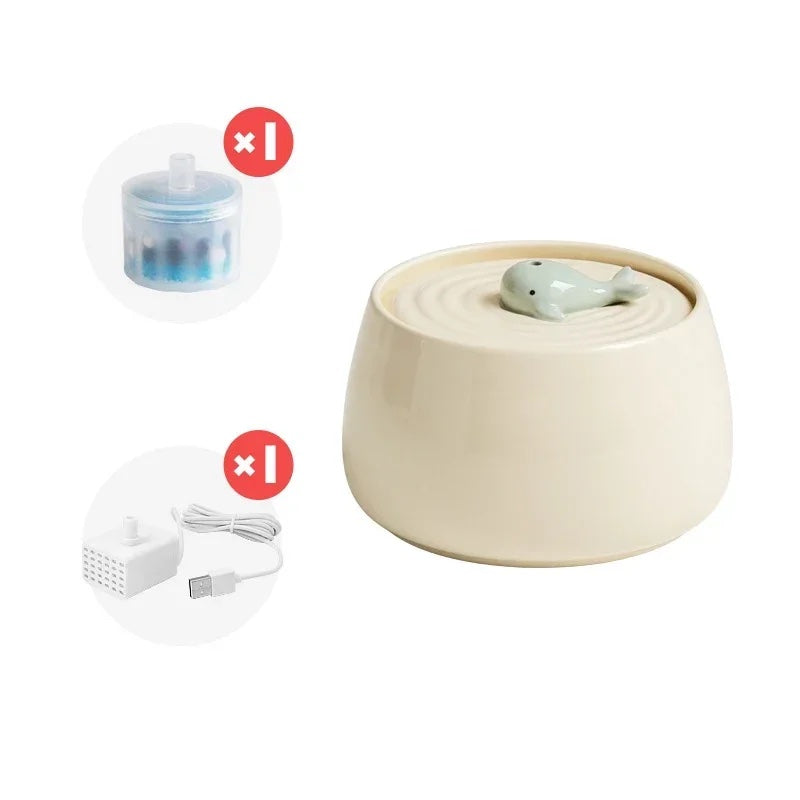 White ceramic pet water fountain with a motive of baby whale displayed with a replacement filter and USB charger.