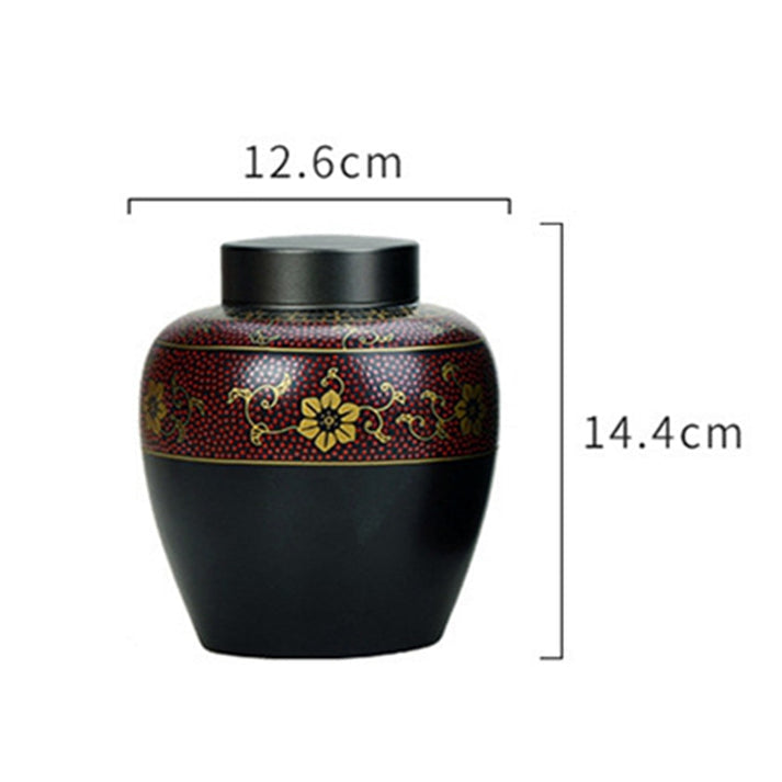Black ceramic pet cremation urn with a red and gold ornament displayed wit its measurements on a white background.