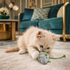 Ginger kitten plays with grey soft mouse cat toy in an art deco living room.