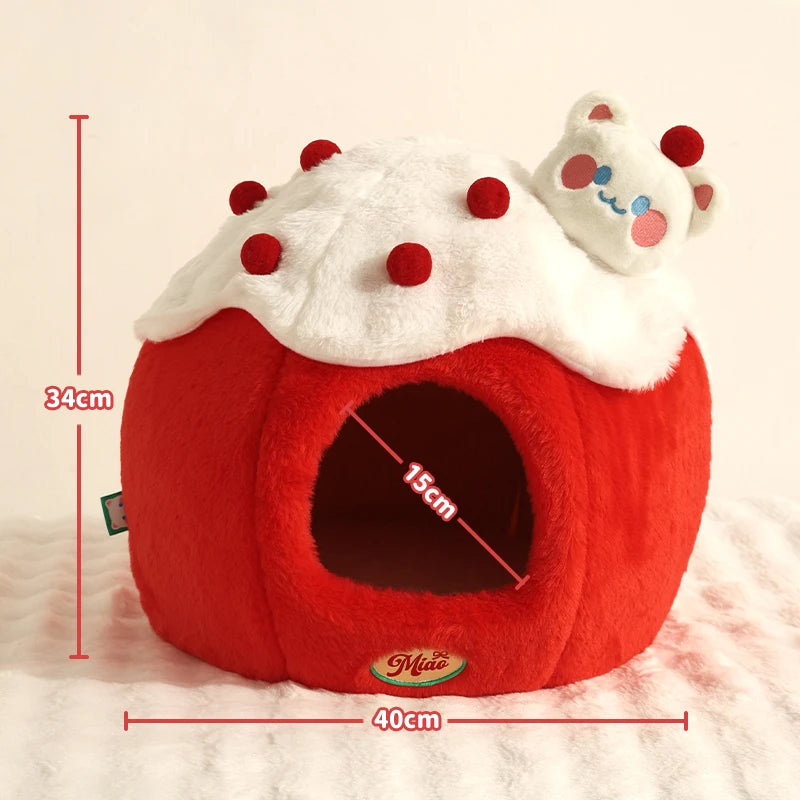 A red and white plush pet house shaped like a cupcake, with a small white cat figurine on top. Red dimension lines show 34 cm height, 15 cm opening width, and 40 cm base width on a light cream background.